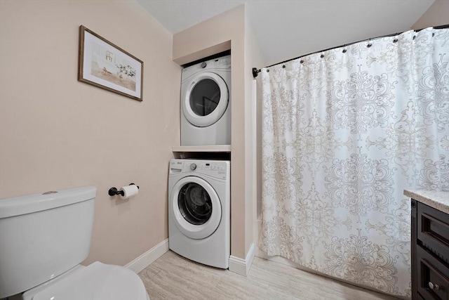 bathroom with hardwood / wood-style floors, vanity, toilet, and stacked washer / dryer