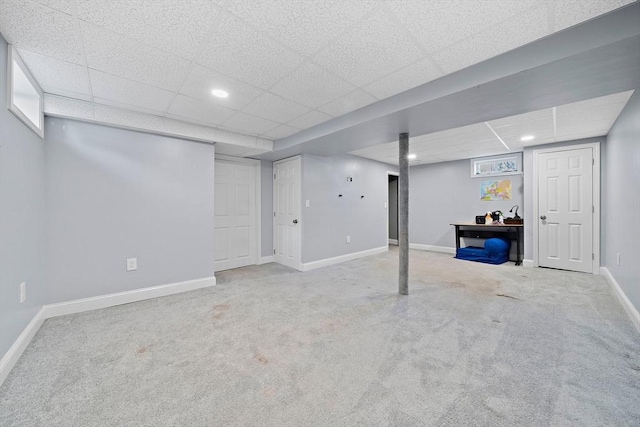 basement with a paneled ceiling and carpet floors