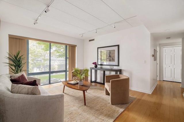 living room with track lighting, light wood-type flooring, visible vents, and baseboards