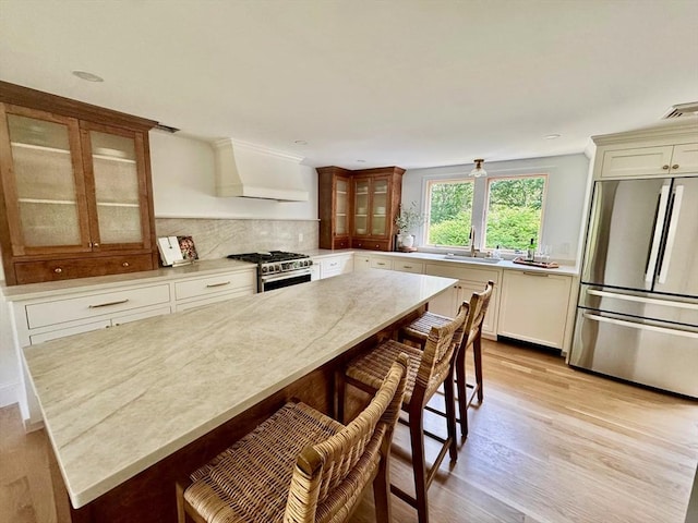 0 Thompson St, Middleboro, MA 02346 - kitchen with appliances with stainless steel finishes, custom range hood, glass insert cabinets, light wood-style floors, and a kitchen bar