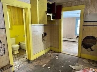 bathroom with a baseboard heating unit, tile walls, and toilet