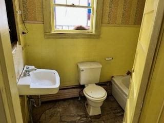 bathroom with toilet, sink, and a bath