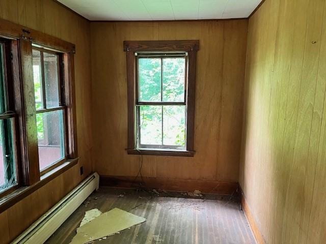 unfurnished room with a baseboard radiator and wood walls