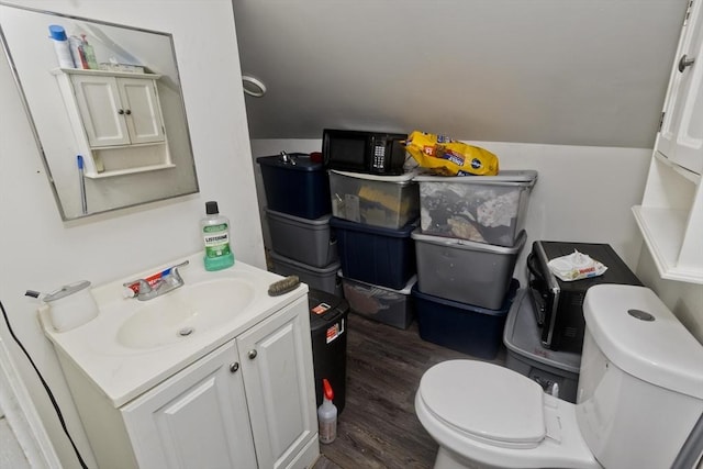 bathroom featuring hardwood / wood-style floors, toilet, vaulted ceiling, and vanity