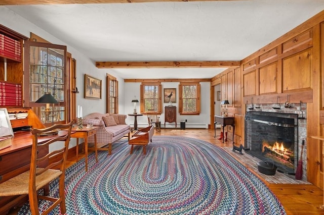 sitting room featuring a fireplace with flush hearth, beam ceiling, light wood finished floors, and a baseboard radiator
