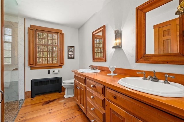 bathroom with radiator, wood-type flooring, a sink, and plenty of natural light