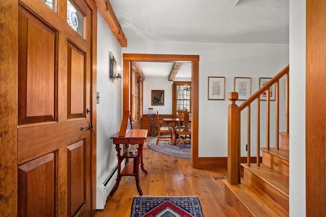 foyer featuring light wood finished floors, a baseboard heating unit, and stairway