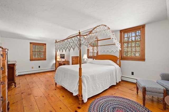 bedroom featuring baseboard heating, a baseboard radiator, and light wood-style floors