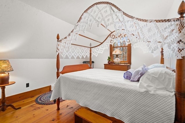 bedroom with lofted ceiling, baseboards, and wood finished floors