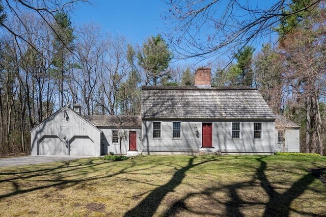 dutch colonial featuring a front yard, an attached garage, a chimney, and aphalt driveway