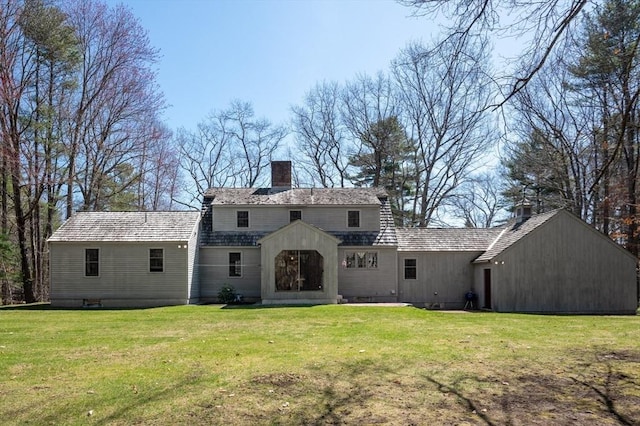 rear view of house featuring a lawn and a chimney