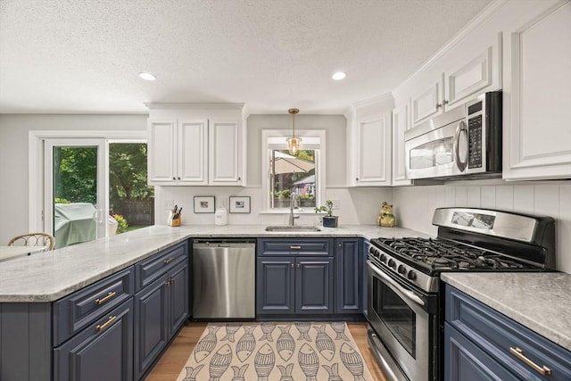 111 Richardson Rd, Barnstable, MA 02632 - kitchen with stainless steel appliances, a sink, blue cabinetry, a peninsula, and white cabinetry