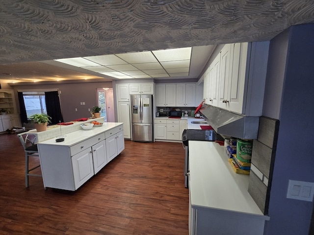 kitchen with white cabinetry, stainless steel fridge with ice dispenser, a breakfast bar, and dark wood-type flooring