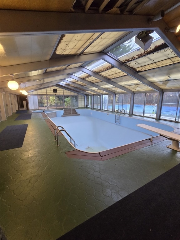 view of swimming pool featuring a skylight and a diving board