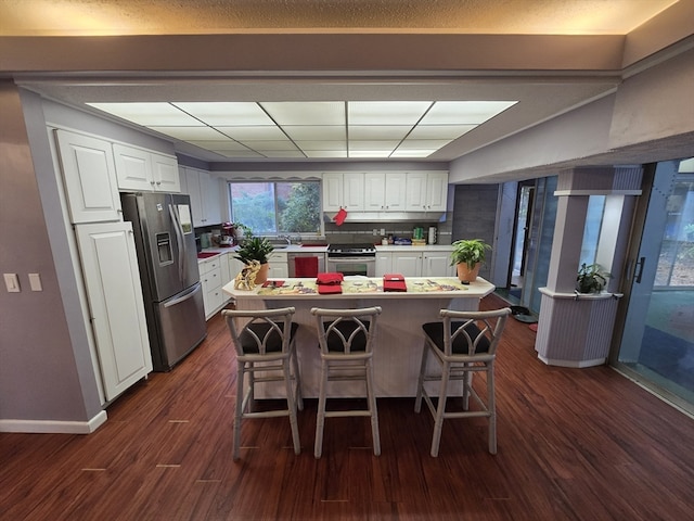 kitchen featuring a center island, dark hardwood / wood-style flooring, a kitchen bar, white cabinets, and appliances with stainless steel finishes