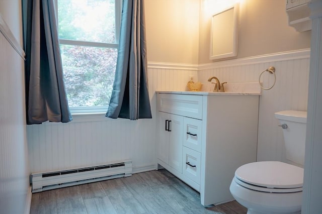 bathroom with vanity, hardwood / wood-style floors, toilet, and baseboard heating