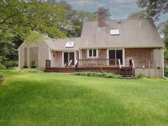 rear view of property featuring a deck and a lawn