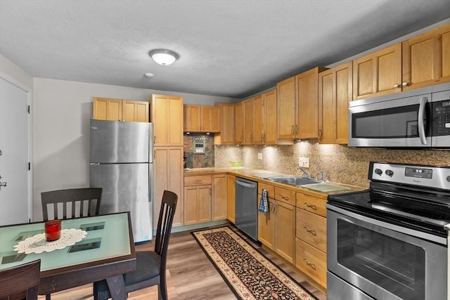 358 Broadway Unit 20, Lynn, MA 01904 - kitchen featuring appliances with stainless steel finishes, light wood-style floors, tasteful backsplash, a sink, and light brown cabinetry