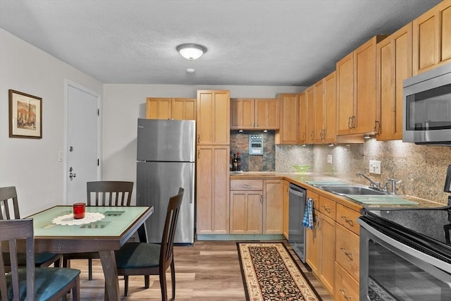 358 Broadway Unit 20, Lynn, MA 01904 - kitchen with stainless steel appliances, light wood finished floors, decorative backsplash, light brown cabinetry, and a sink
