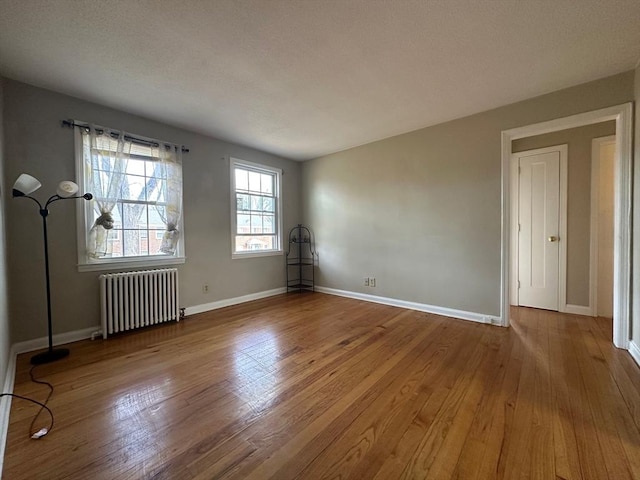 empty room with radiator heating unit and light hardwood / wood-style floors