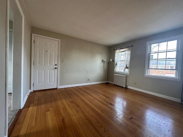 unfurnished room with hardwood / wood-style floors and radiator heating unit