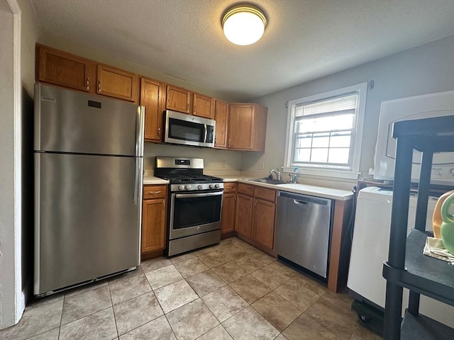 kitchen featuring stainless steel appliances, sink, a textured ceiling, and light tile patterned floors