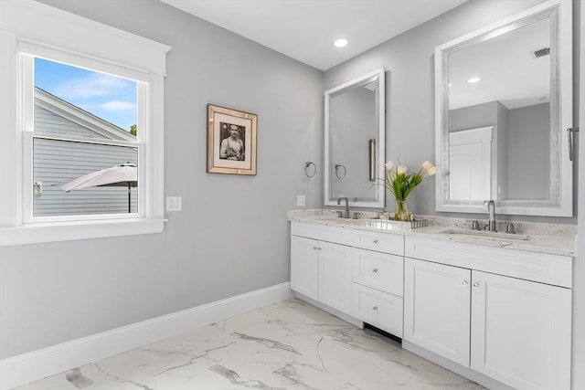 full bath with marble finish floor, baseboards, double vanity, and a sink