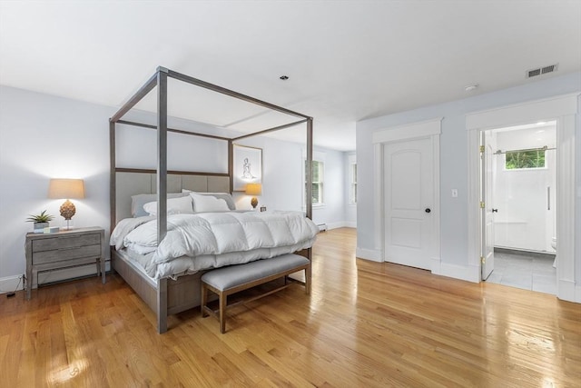 bedroom with light wood-type flooring, ensuite bath, baseboards, and visible vents