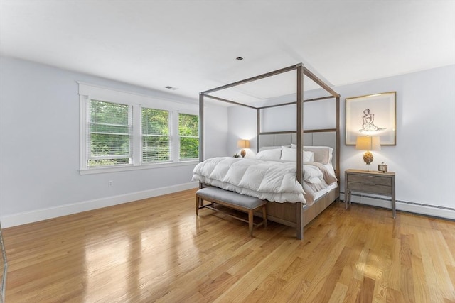 bedroom with baseboards, visible vents, light wood-type flooring, and a baseboard radiator