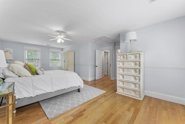 bedroom with light wood-style floors, baseboards, attic access, and ceiling fan