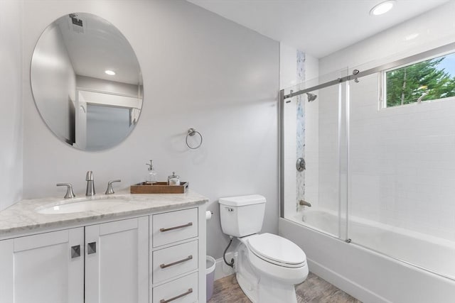 full bathroom with combined bath / shower with glass door, toilet, vanity, wood finished floors, and baseboards