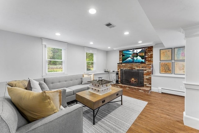 living room featuring visible vents, a baseboard radiator, a fireplace, recessed lighting, and light wood-style floors