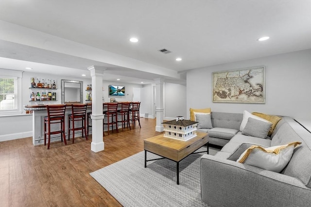 living area with wood finished floors, bar area, baseboards, visible vents, and recessed lighting
