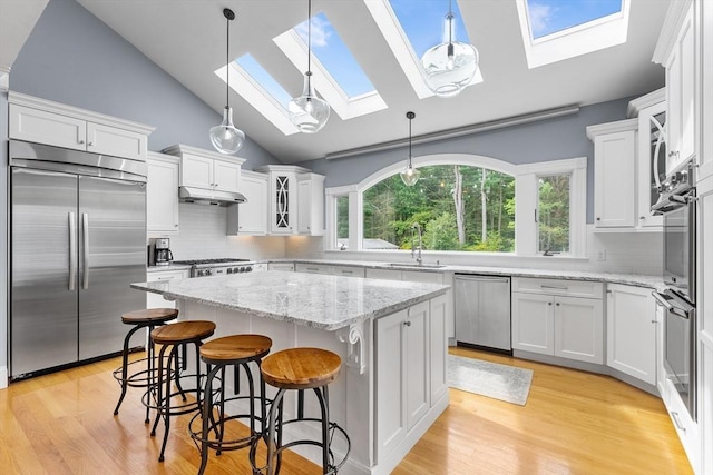kitchen with under cabinet range hood, white cabinetry, a center island, and appliances with stainless steel finishes