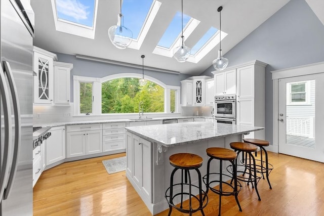 kitchen with appliances with stainless steel finishes, white cabinetry, a skylight, and a sink