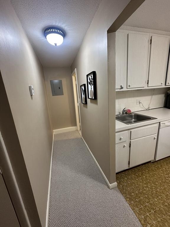 hall featuring sink, a textured ceiling, and electric panel