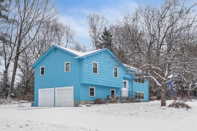 snow covered house featuring a garage