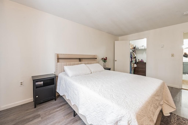 bedroom featuring a closet, a spacious closet, baseboards, and wood finished floors