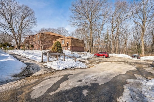 view of snowy exterior with brick siding and driveway