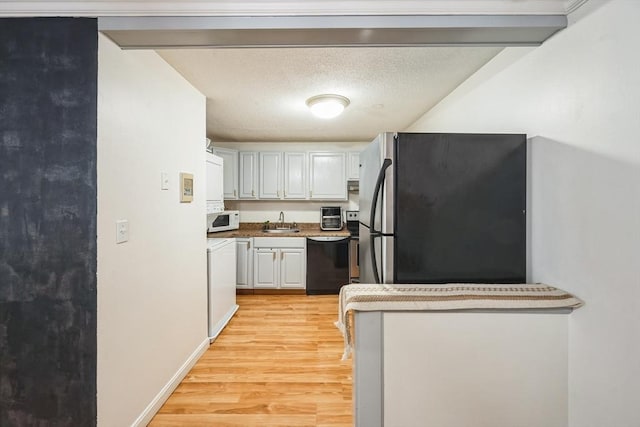 kitchen with a textured ceiling, a sink, freestanding refrigerator, dishwasher, and light wood finished floors