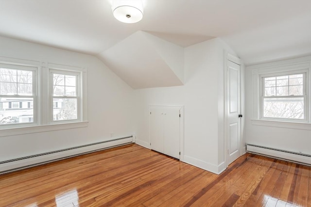 additional living space featuring lofted ceiling, light hardwood / wood-style floors, and a baseboard heating unit