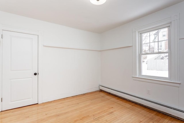 spare room featuring hardwood / wood-style flooring and a baseboard heating unit