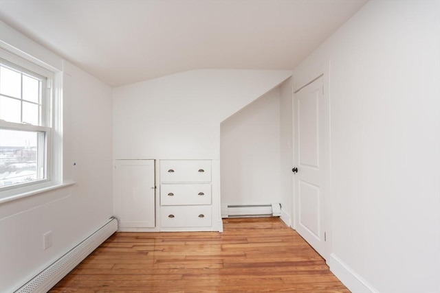 interior space with vaulted ceiling, a baseboard heating unit, and light hardwood / wood-style floors