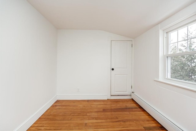 spare room featuring lofted ceiling, a baseboard radiator, light hardwood / wood-style floors, and a healthy amount of sunlight