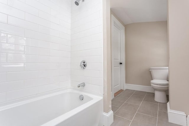 bathroom with toilet, tiled shower / bath combo, and tile patterned flooring