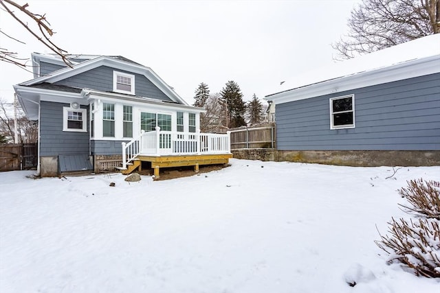 snow covered rear of property with a deck