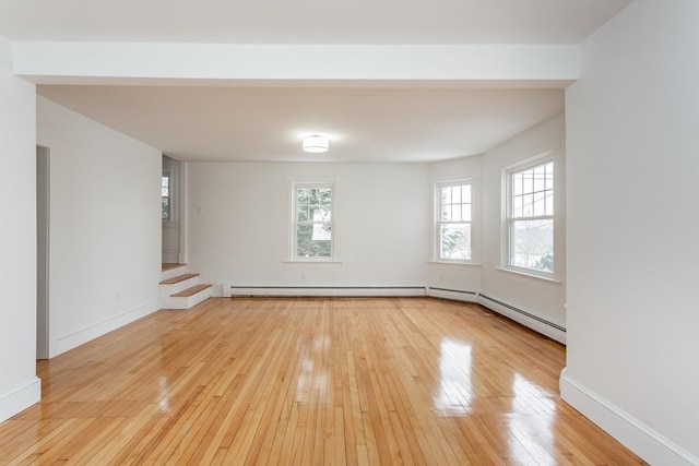 empty room with a baseboard heating unit and light hardwood / wood-style floors