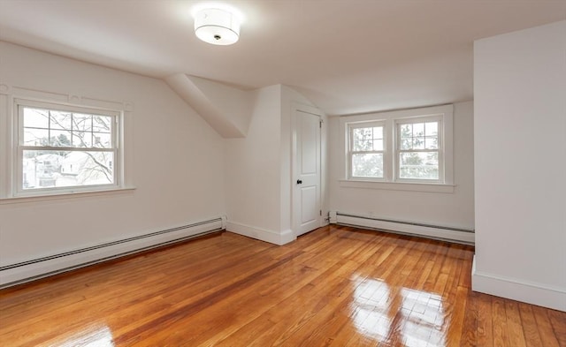 additional living space with a baseboard radiator, plenty of natural light, and light hardwood / wood-style floors