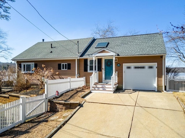 view of front facade with roof with shingles, concrete driveway, an attached garage, and fence