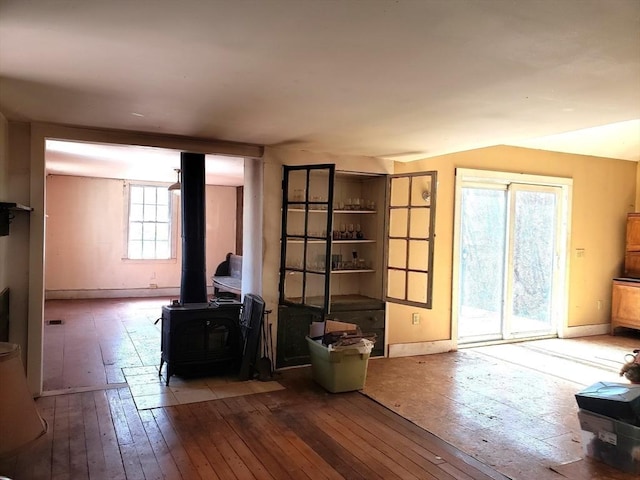 unfurnished living room with hardwood / wood-style flooring, a wood stove, and baseboards